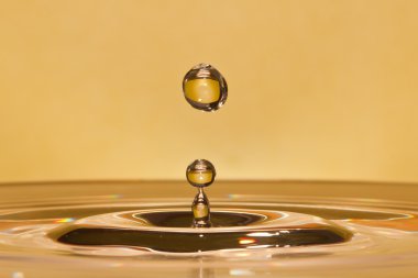 Closeup of falling water-drop in a yellow liquid clipart