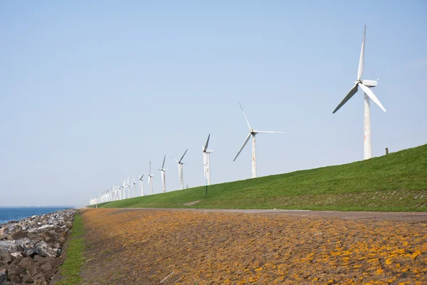 Moinhos de vento perto do mar ao longo de um dique holandês — Fotografia de Stock
