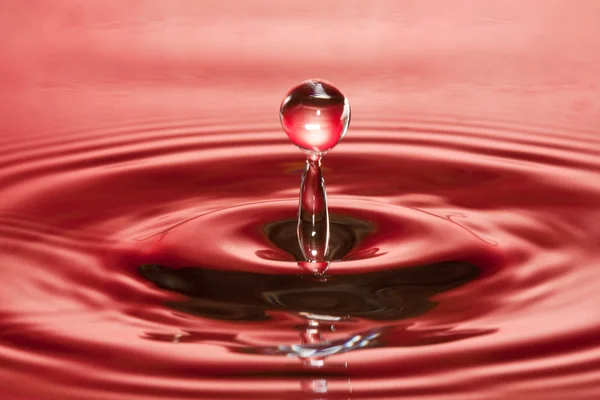 stock image Closeup of falling water-drop in a red liquid