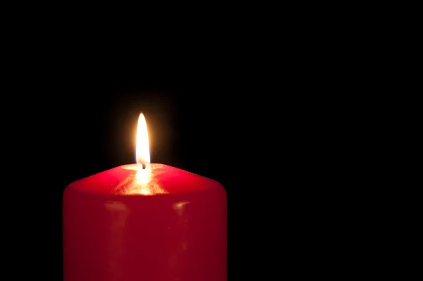 Red candle isolated against a black background — Stock Photo, Image