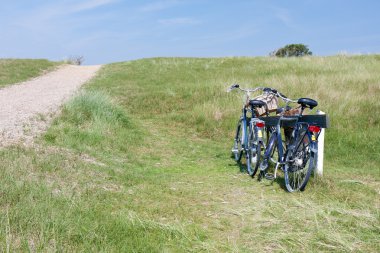 Two bicycles parked in the dunes in Netherlands. clipart