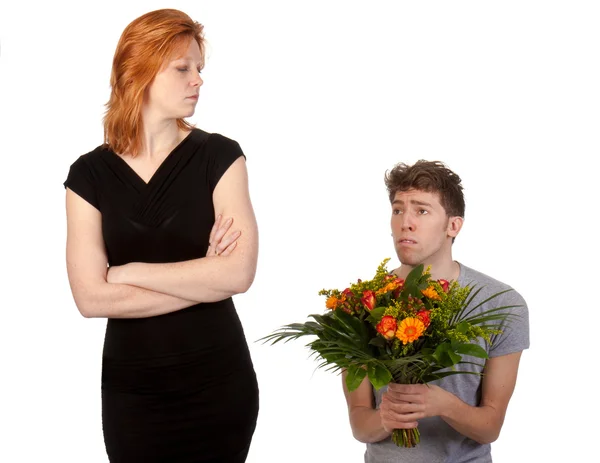 Genç çocuk sinirli kız arkadaşına bir demet çiçek sunan — Stok fotoğraf