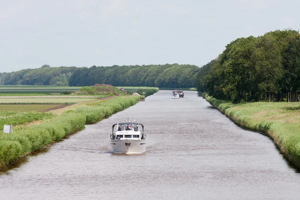 Голландский канал с яхтами удовольствия через зеленые луга — стоковое фото