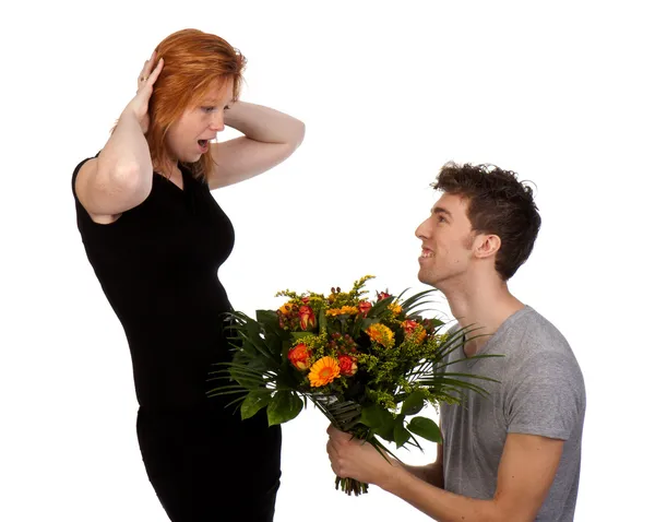Junger Mann bietet seiner überraschten Freundin einen großen Blumenstrauß an — Stockfoto
