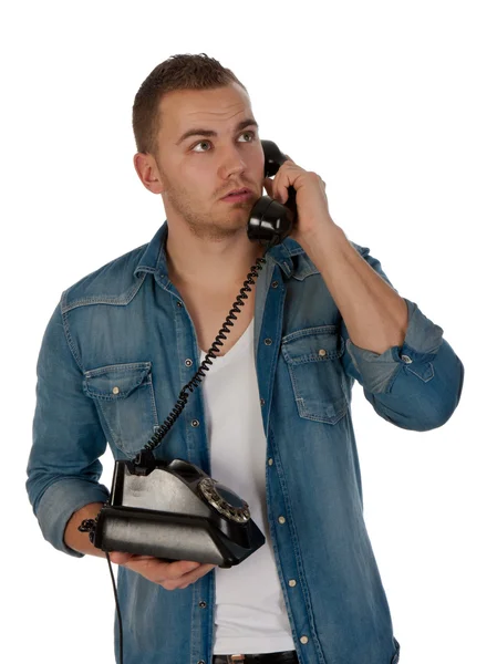 Молодой человек делает телефонный звонок со старым телефоном против... — стоковое фото