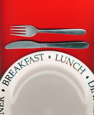 Knife and fork with white plate on red background clipart