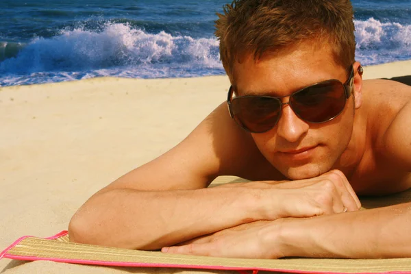Mann sonnt sich am Strand — Stockfoto