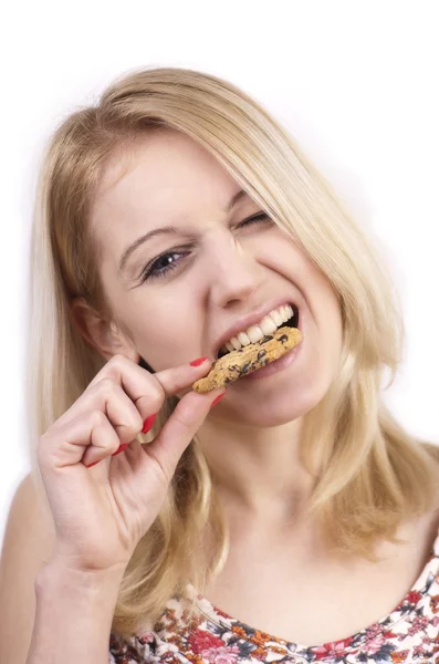 Young woman eating cookie with grimace — Stock Photo, Image