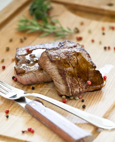 Steaks op een houten bord — Stockfoto