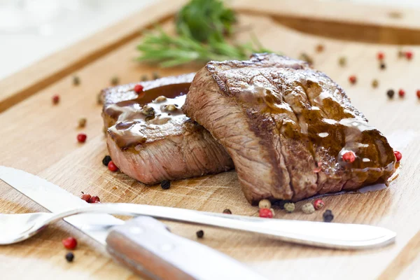 Dva chutné steaky na dřevěném prkénku — Stock fotografie