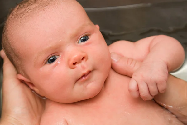 Baby held in bath by hands — Stock Photo, Image