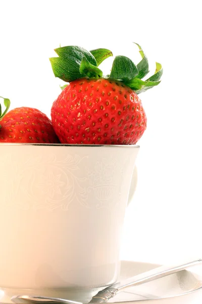 Färska röda jordgubbar i vit tekopp med fat och sked på — Stockfoto
