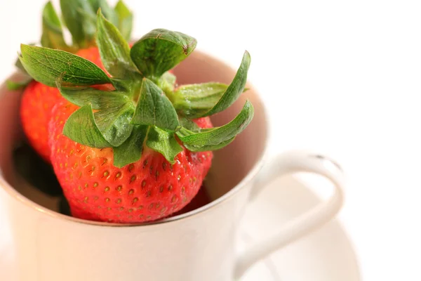 Färska röda jordgubbar inuti vita Kina tekopp på tefat — Stockfoto