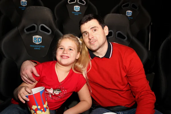 父亲和女儿看一场电影在电影院 免版税图库照片