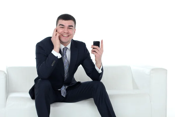 Młody mężczyzna rozmawia przez telefon, siedząc na kanapie na białym tle na whi — Zdjęcie stockowe