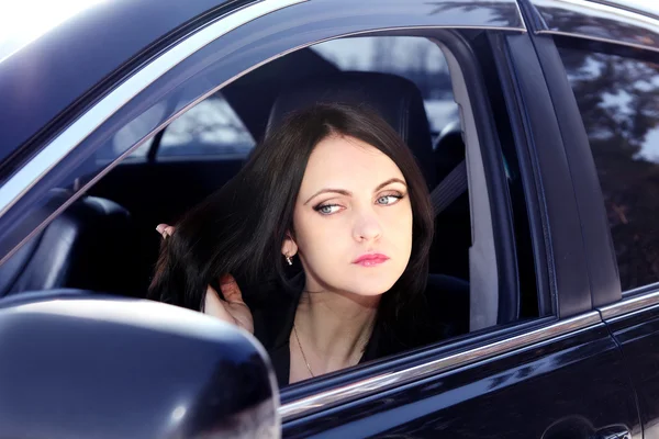 Kvinna sitter i bilen och ser i spegeln — Stockfoto