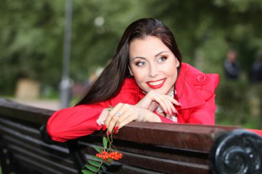 Young woman sitting on a bench in the park and in the hands hold