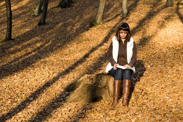 Flickan läsa i höst skog — Stockfoto