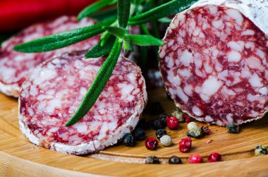 Close up salami peper corns rosemary on cutting board clipart