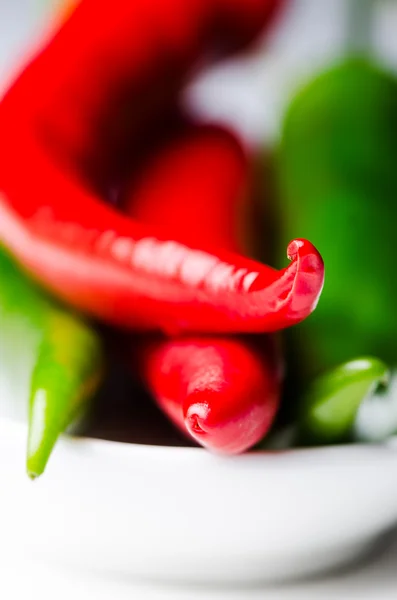 Green and red chili peppers in white bowl — Stock Photo, Image