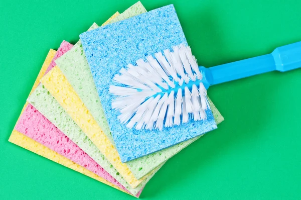 Brush and multi color sponges on green background — Stock Photo, Image