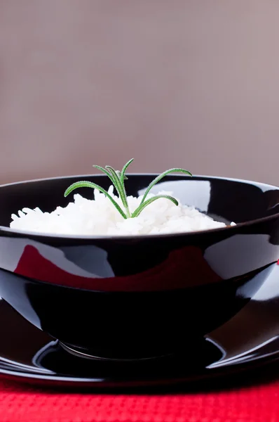 Rijst in zwarte ronde kom op rood tafellaken — Stockfoto