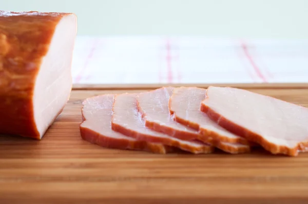 Ham cut into slices on a wooden board close up — Stock Photo, Image