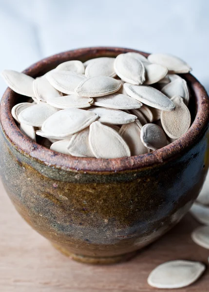 Ciotola di ceramica piena di semi di zucca su sfondo tavolo da cucina — Foto Stock
