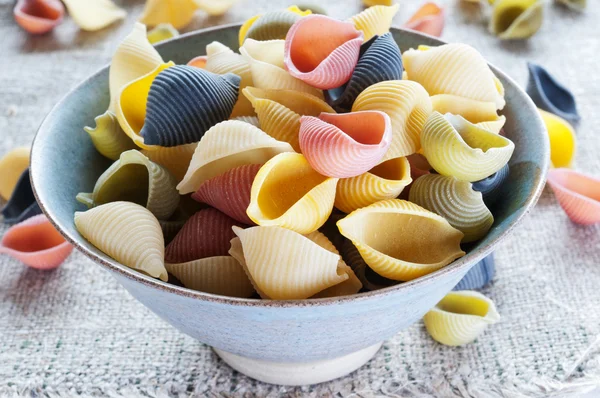 Multi colored pasta in bowl on coarse cloth — Stock Photo, Image