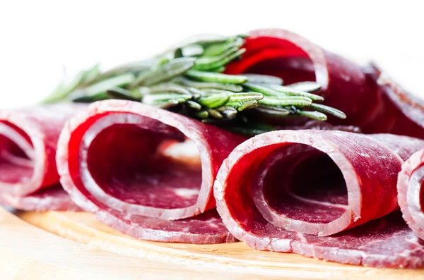 Rolls of cured smoked beef on wooden board — Stock Photo, Image