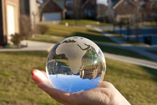 My world. Glass globe reflecting a street and blue sky.
