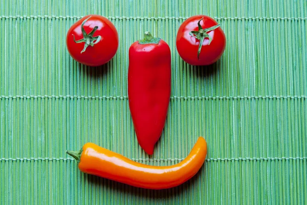 stock image Smiling face of fresh vegetables on green bamboo placemat.