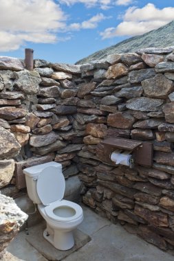 Public outdside stone restroom without roof at desert clipart