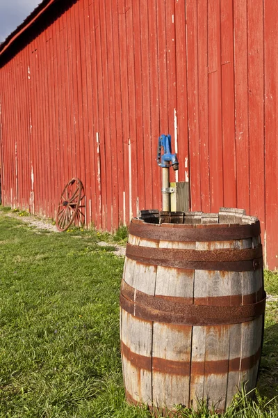 Old wooden barrel beside a red barn. — Stock Photo, Image