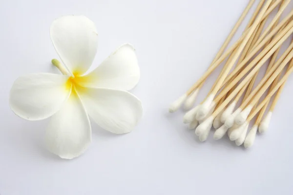 Tampone di cotone utilizzato per la pulizia delle orecchie e fiori tropicali isolati — Foto Stock