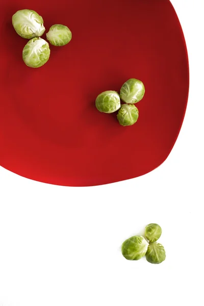 Брюссельская капуста лежит на красной тарелке — стоковое фото
