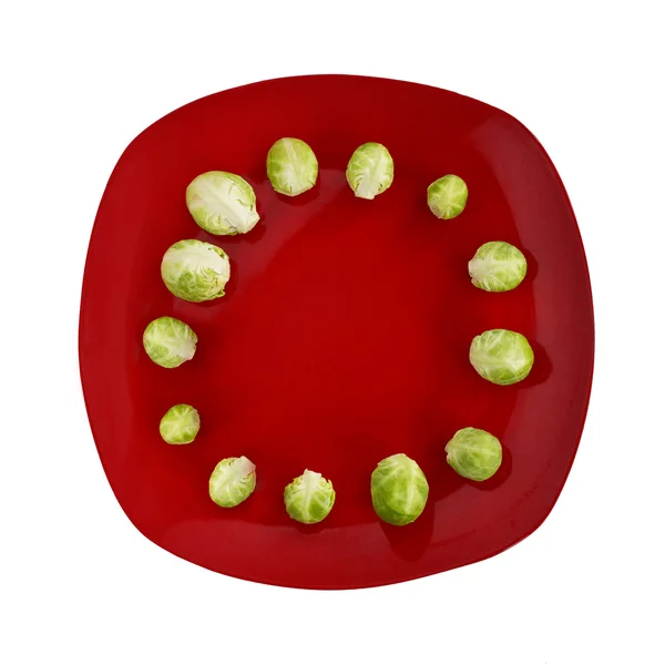 Brussels sprouts lies on red plate — Stock Photo, Image