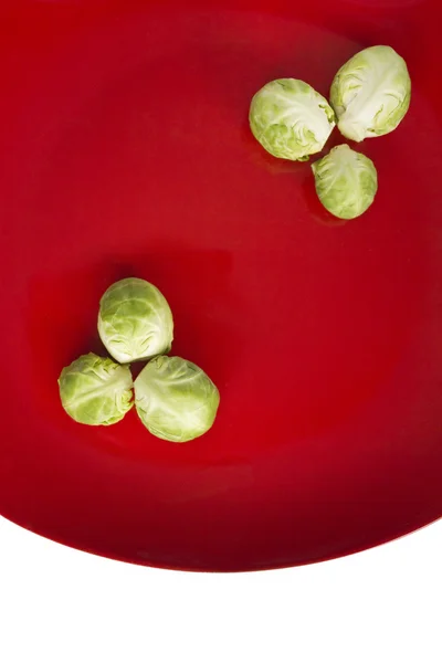 Λαχανάκια Βρυξελλών βρίσκεται στο κόκκινο πιάτο — Φωτογραφία Αρχείου