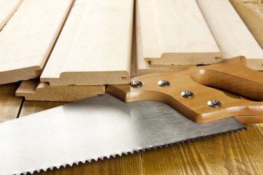 Carpenter's saw is on a woode planks clipart