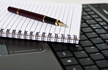 kalem, not defteri ve masanın üstünde laptop