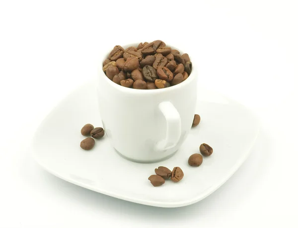 Káva pohár přetéká tmavě pražená kávová zrna — Stock fotografie