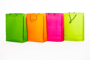 Assorted colored shopping bags including yellow, orange, pink and green on a white background clipart