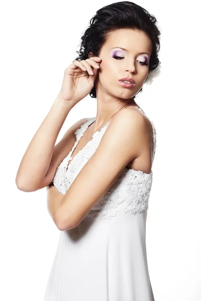 Feliz novia hermosa chica morena sexy en vestido de novia blanco con peinado y maquillaje brillante con flor en el pelo aislado en blanco — Foto de Stock