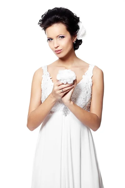 Joyeux sexy belle mariée fille brune en robe de mariée blanche avec fleur dans les mains avec coiffure et maquillage lumineux avec fleur dans les cheveux isolés sur blanc — Photo