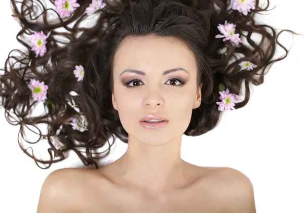 Jolie belle fille couchée avec des fleurs brillantes dans ses cheveux maquillage lumineux — Photo
