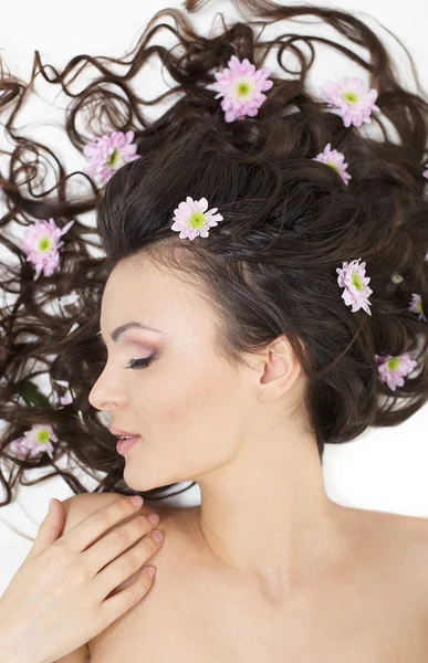 Jolie belle fille couchée avec des fleurs brillantes dans ses cheveux maquillage lumineux — Photo