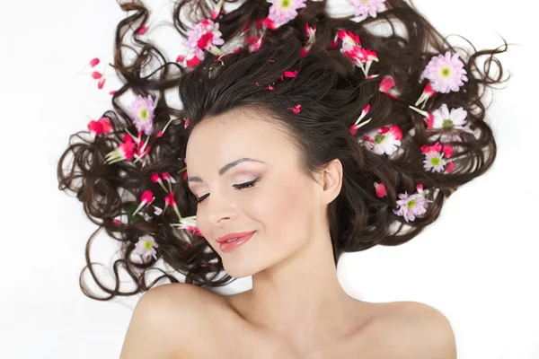 Pretty beautiful girl lying with bright red flowers in her hair bright make — Stock Photo, Image