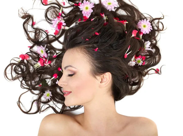 Menina bonita deitado com flores vermelhas brilhantes em seu cabelo brilhante fazer — Fotografia de Stock