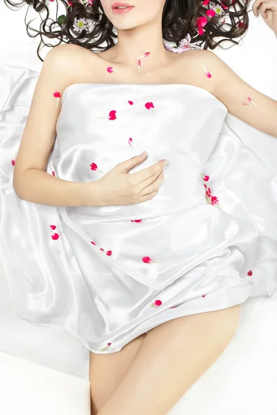 Body of young girl on the covered with bed sheet in flowers — Stock Photo, Image