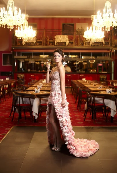 Schöne Braut im ungewöhnlichen Brautkleid im Restaurant mit Siegerpokal — Stockfoto